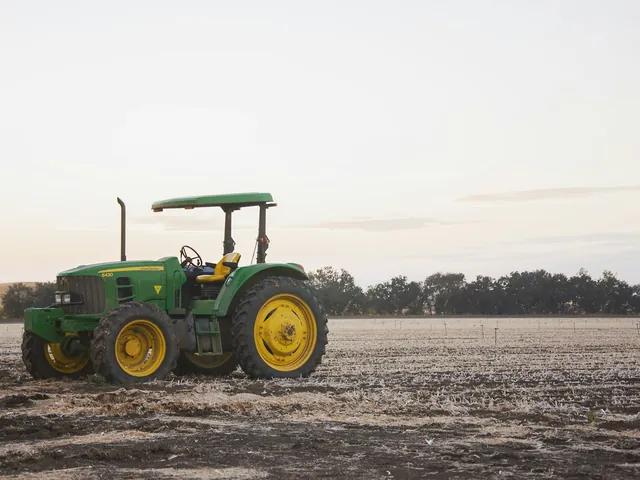 Green tractor standing in a ploughed field