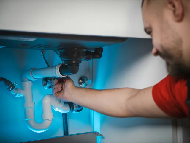 Plumber at work under a sink